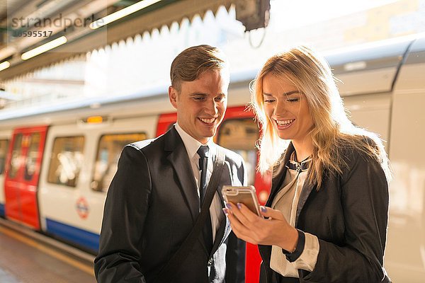 Geschäftsmann und Geschäftsfrau texten auf dem Bahnsteig  U-Bahnhof  London  UK