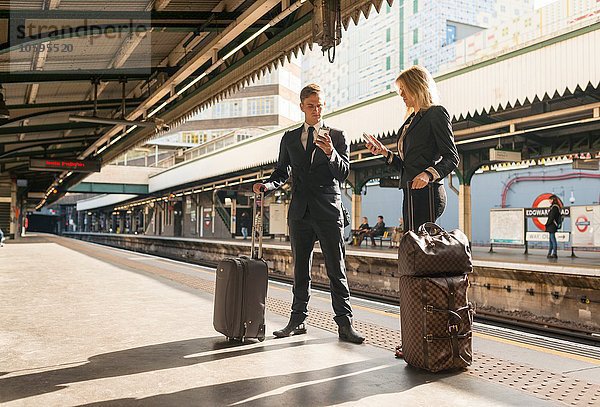 Geschäftsmann und Geschäftsfrau texten auf dem Bahnsteig  U-Bahnhof  London  UK