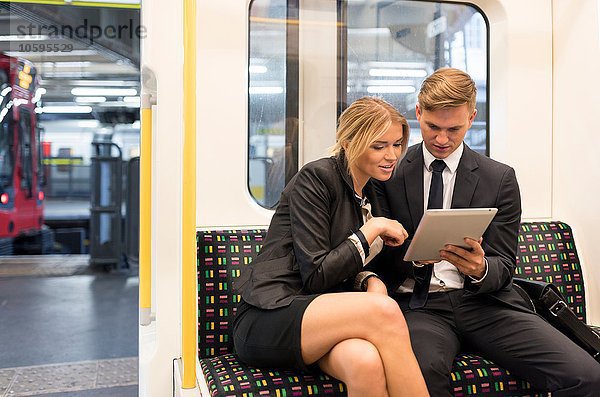 Geschäftsmann und Geschäftsfrau teilen sich ein digitales Tablett  London Underground  UK