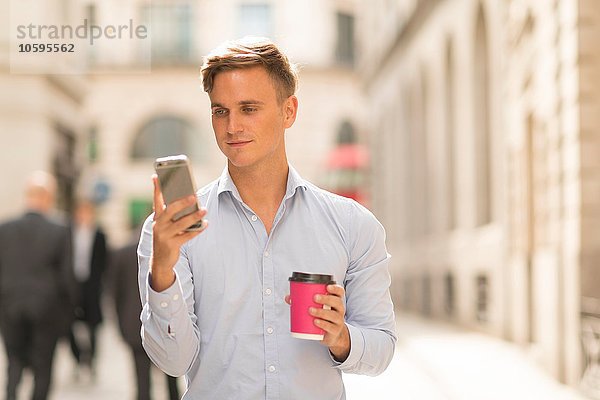 Mann mit Kaffee zum Mitnehmen per Smartphone