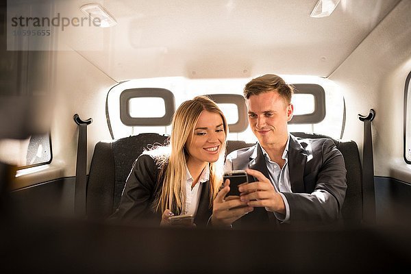 Geschäftsmann und Geschäftsfrau mit Smartphone im schwarzen Taxi  London  UK
