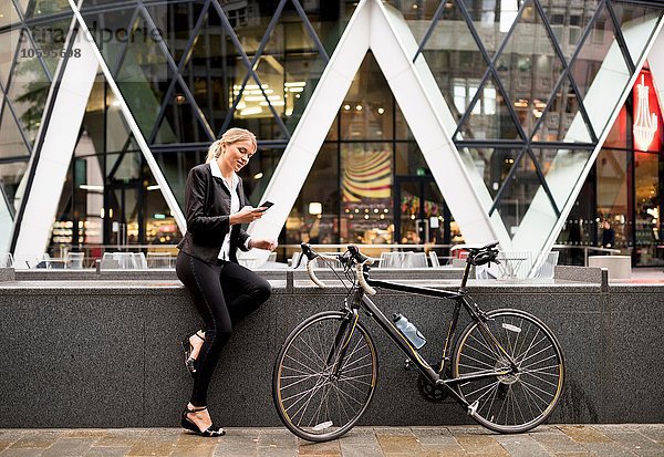 Geschäftsfrau mit Fahrrad draußen 30 St Mary Axe  London  UK