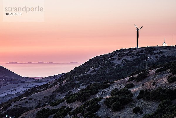 Windkraftanlagen auf dem Berggipfel gegen den dramatischen orangefarbenen Himmel  Castelsardo  Sardinien  Italien