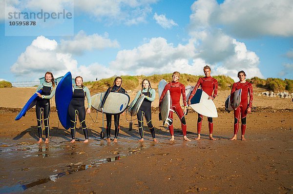 Gruppe von Surfern  die am Strand stehen und Surfbretter halten