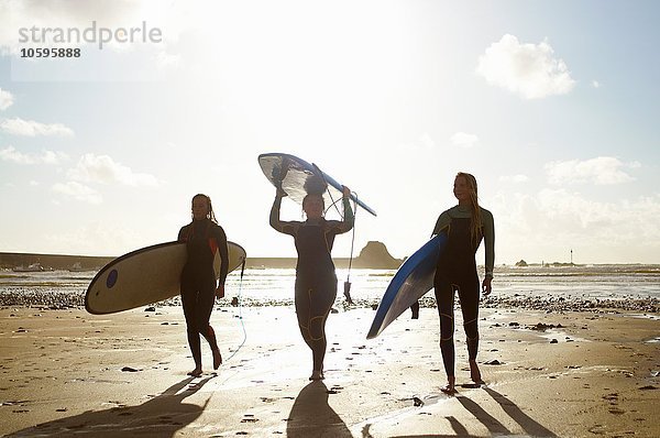 Drei Freundinnen am Strand  die Surfbretter halten.