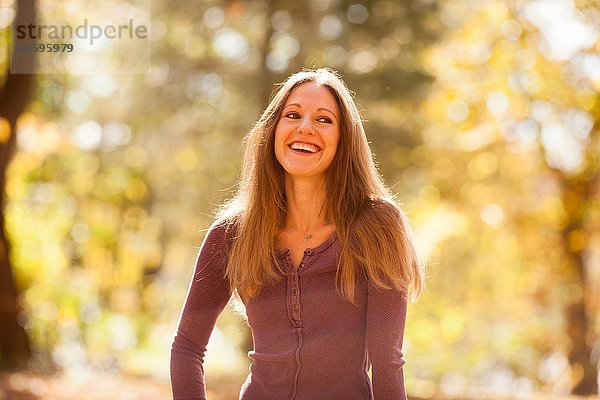 Sonnenlichtporträt eines langhaarigen jungen Mannes im Herbstwald