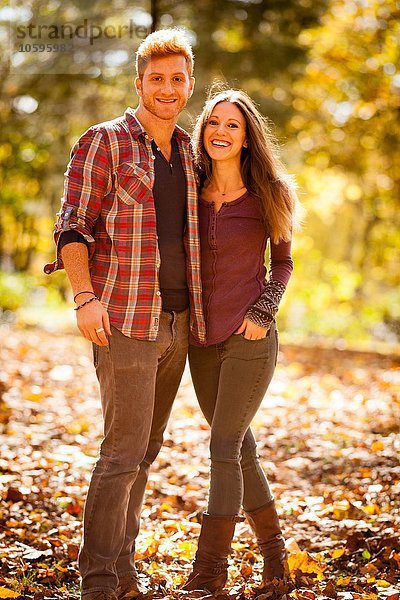Sonniges Porträt eines jungen Paares im Herbstwald
