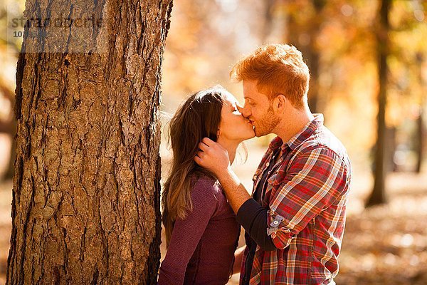 Romantisches junges Paar beim Küssen im Herbstwald