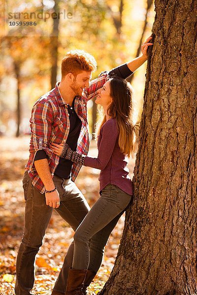 Romantisches junges Paar lehnt sich im Herbstwald an den Baum