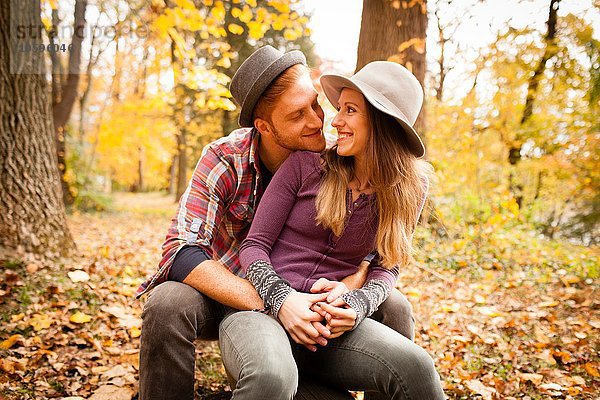 Romantisches junges Paar im Herbstwald sitzend