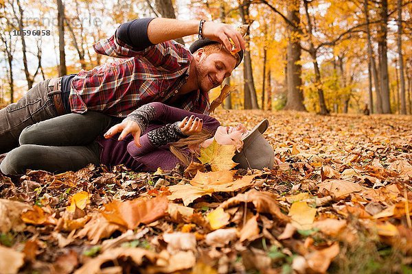 Junges Paar kämpft mit Herbstblättern im Wald