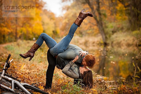 Romantisches junges Paar  das im Herbst am Flussufer herumtobt.