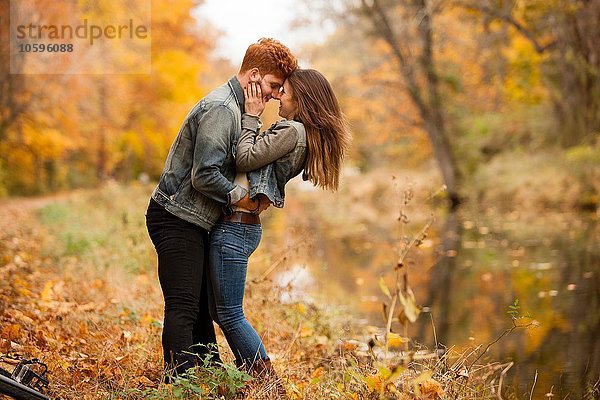 Romantisches junges Paar am Flussufer im Herbst