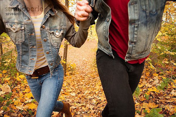 Ausschnitt eines romantischen jungen Paares  das durch den Herbstwald rennt.
