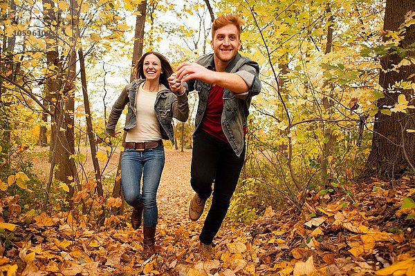 Romantisches junges Paar läuft durch den Herbstwald