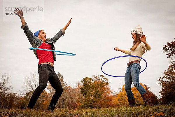 Junges Paar spielt mit Plastikreifen im Herbstpark