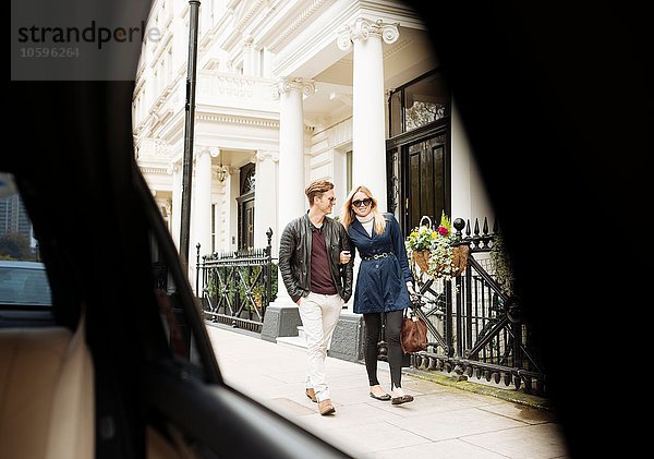 Autofensteransicht des jungen Paares  das auf der Straße spazieren geht  London  England  UK
