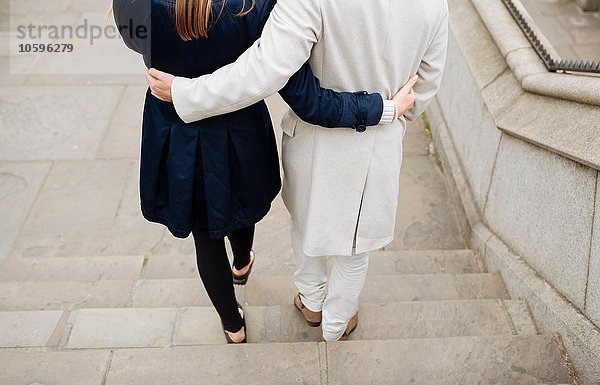 Rückansicht eines romantischen Paares  das die Stadttreppe hinuntergeht.