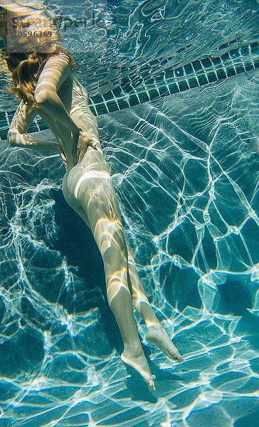 Unterwasser-Seitenansicht der nackten jungen Frau im Schwimmbad  Hände auf den Hüften