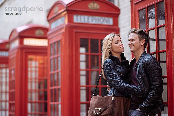 Romantisches junges Paar neben roten Telefonzellen  London  England  UK