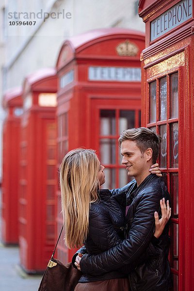Romantisches junges Paar umarmt neben roten Telefonzellen  London  England  UK