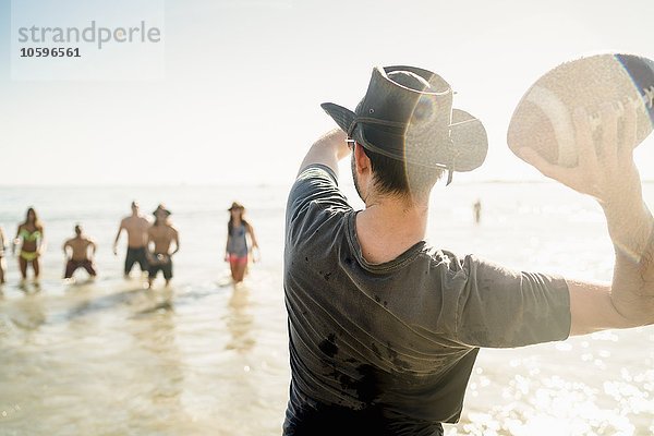 Junger Mann wirft American Football Ball an Freunde im Meer in Newport Beach  Kalifornien  USA