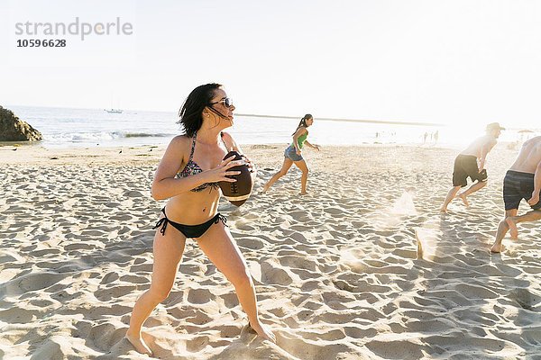 Männliche und weibliche erwachsene Freunde spielen American Football am Newport Beach  Kalifornien  USA