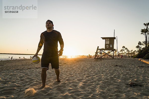 Junger Mann beim Beachvolleyball bei Sonnenuntergang  Newport Beach  Kalifornien  USA