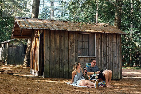Junges Paar entspannt sich vor der Hütte im Wald