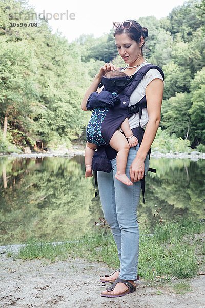 Porträt einer jungen Frau mit Tochter im Tragetuch am Flussufer