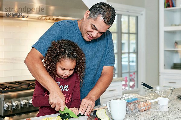 Vater hilft Tochter Gemüse in der Küche hacken