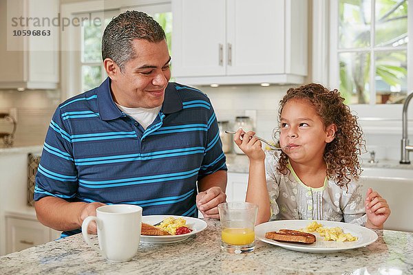 Vater und Tochter Seite an Seite an der Küchenzeile beim Frühstücken