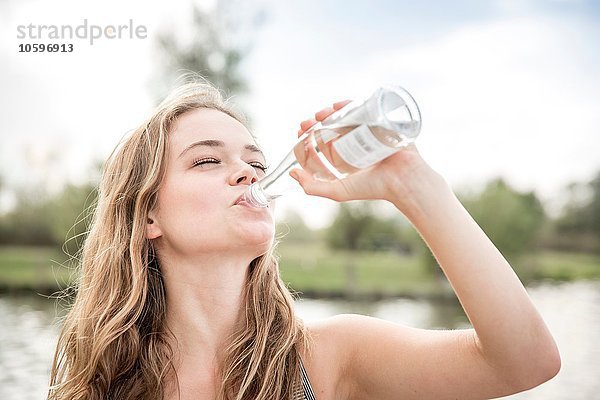 Junge Frau trinkt Wasser aus der Flasche  im Freien