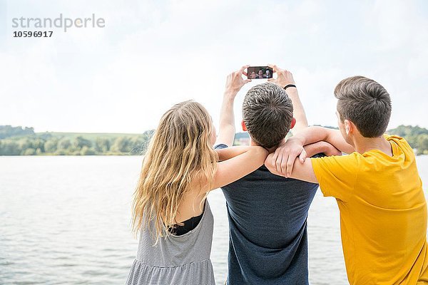 Drei junge Erwachsene beim Selbstporträt mit dem Smartphone  Rückansicht
