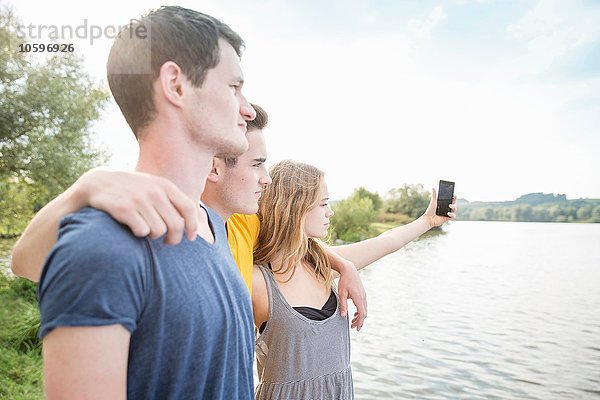 Drei junge Erwachsene beim Selbstporträt  mit dem Smartphone  im Freien