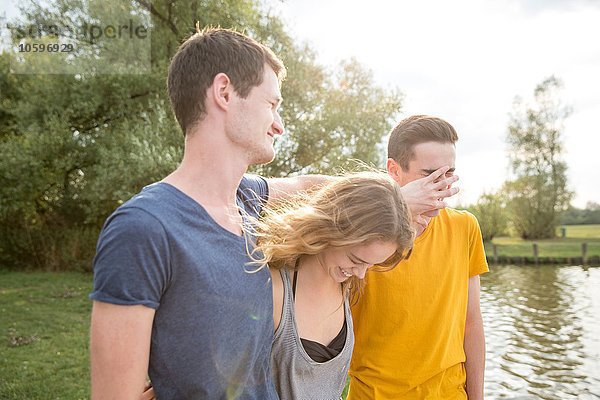 Gruppe junger Erwachsener  am See stehend  herumalbernd  lachend