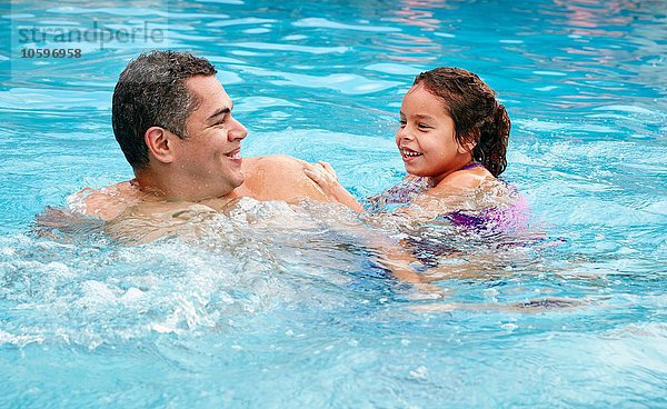 Kopf und Schultern von Vater und Tochter im Schwimmbad lächelnd