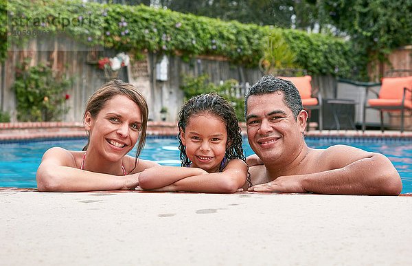 Kopf und Schultern des Mädchens im Schwimmbad mit lächelndem Blick der Eltern auf die Kamera