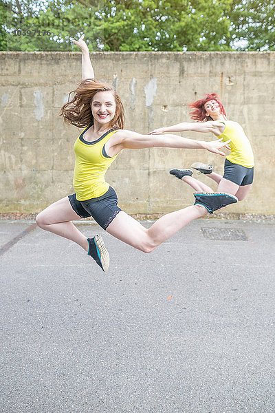 Junge Frauen springen vor der Betonmauer
