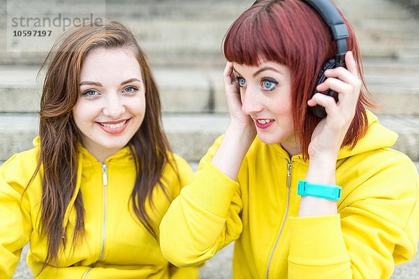 Junge Frauen mit Kopfhörer auf der Treppe