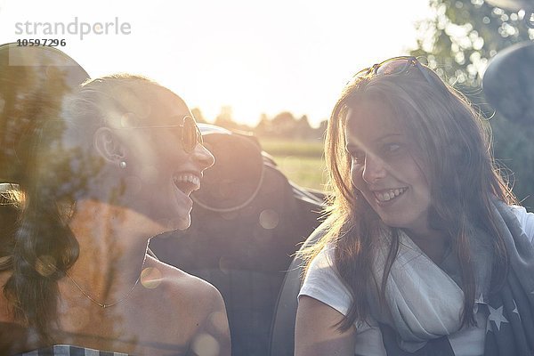 Zwei junge Freundinnen beim Plaudern im Cabriolet