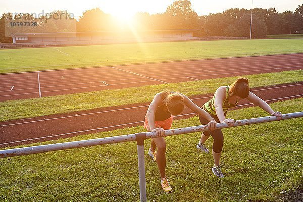 Zwei junge Frauen trainieren am Handlauf auf der Rennstrecke