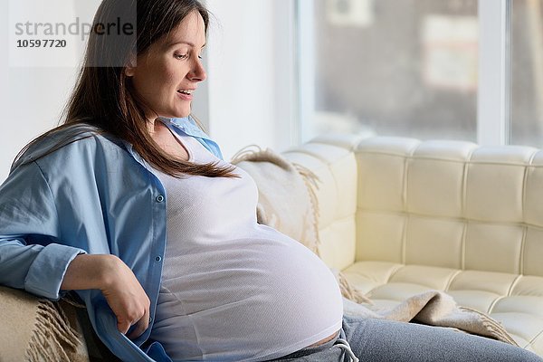 Schwangere Frau auf dem Sofa sitzend