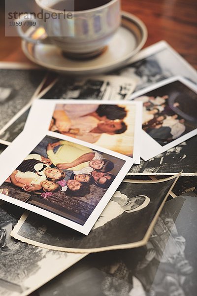 Stapel von Familienfotos auf dem Tisch  neben der Teetasse