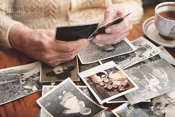 Seniorin am Tisch sitzend  alte Fotos durchsehend  Mittelteil