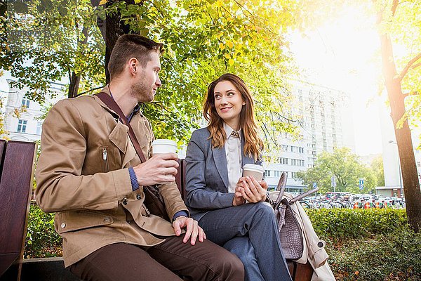 Lässiger Geschäftsmann und Frau im Park mit Kaffee