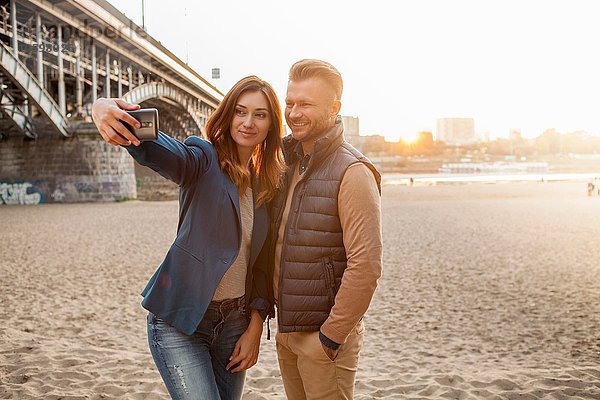 Mittleres erwachsenes Paar durch Brücke  die selfie am Telefon nimmt
