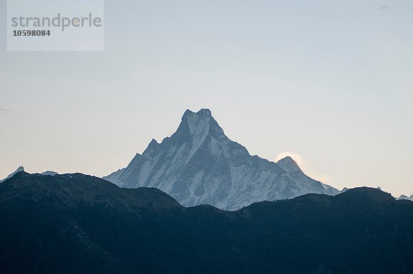 Schneebedeckter Berggipfel gegen dunkle Bergkette  Nepal