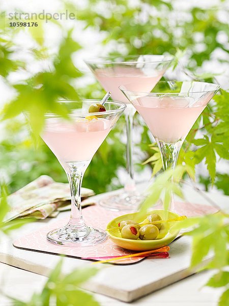 Drei Gläser rosa Grapefruit und Martini-Cocktails mit grünen Oliven