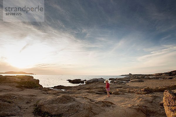 Weibliches Kleinkind auf Küstenfelsen bei Sonnenuntergang  Calvi  Korsika  Frankreich